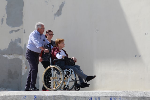 Grandfather and sister helping wheelchair user